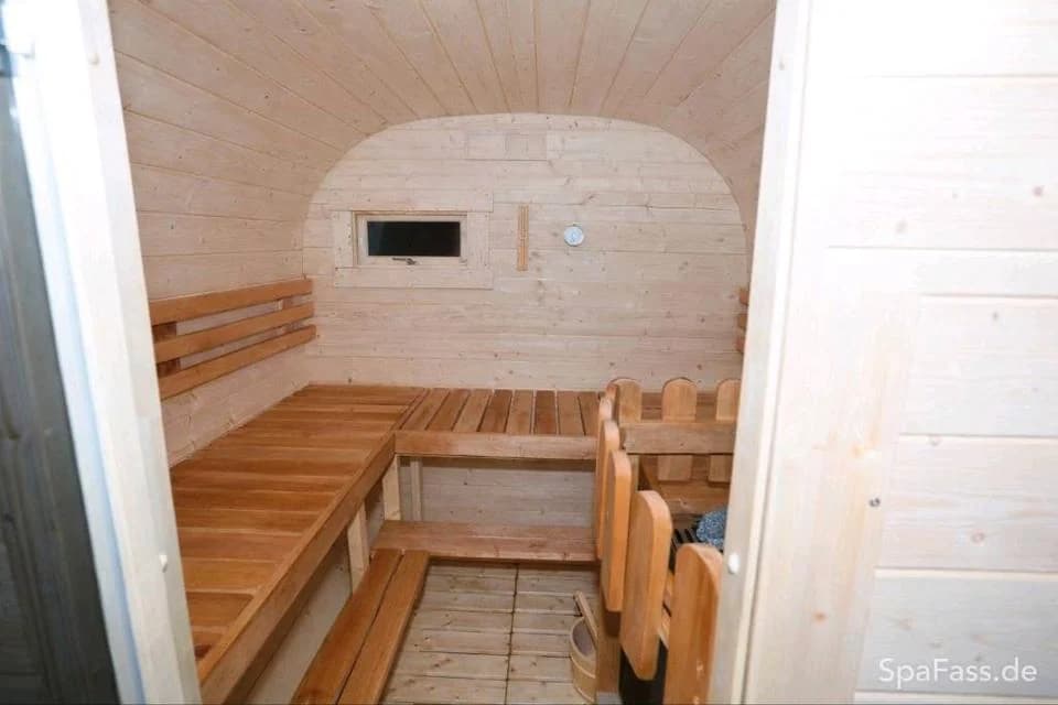 Saunaraum mit Holzbänken und Ofenschutz